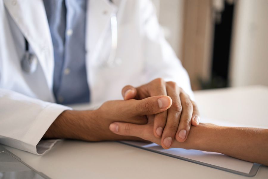 A doctor holding the hand of a patient in the doctor's office.